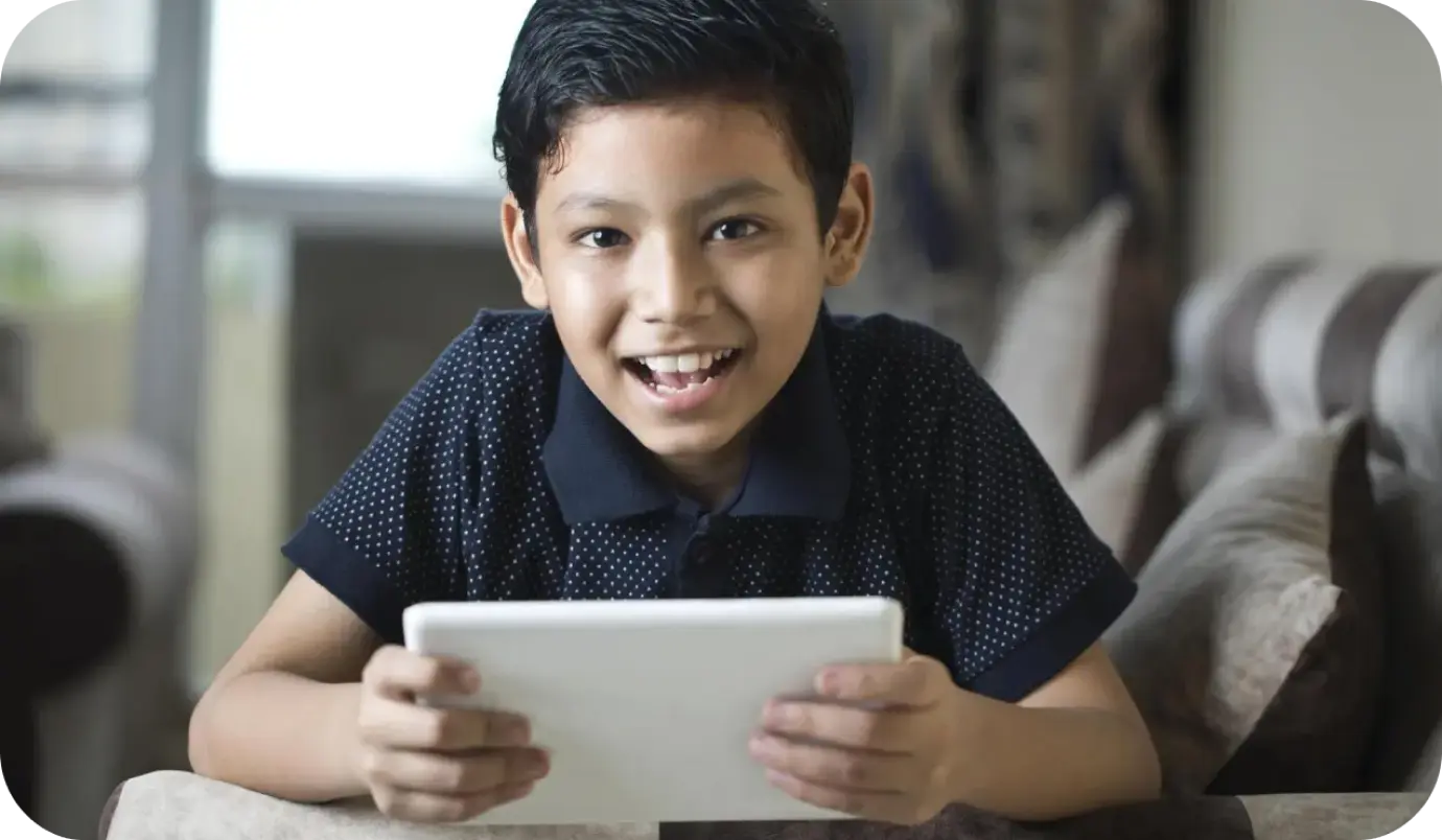 A student smiling while holding a learning tablet received through an education program supported by a social sector organization, symbolizing access to personalized and digital education opportunities.